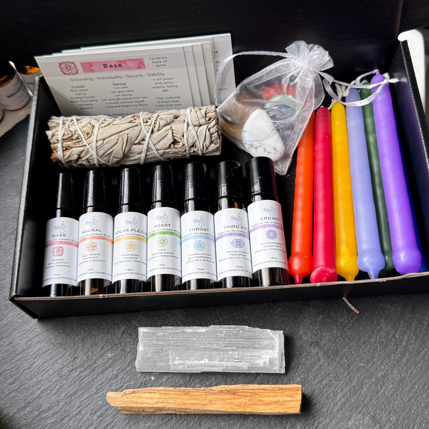 Set of essential oils, candles, and other items in a box on a dark surface