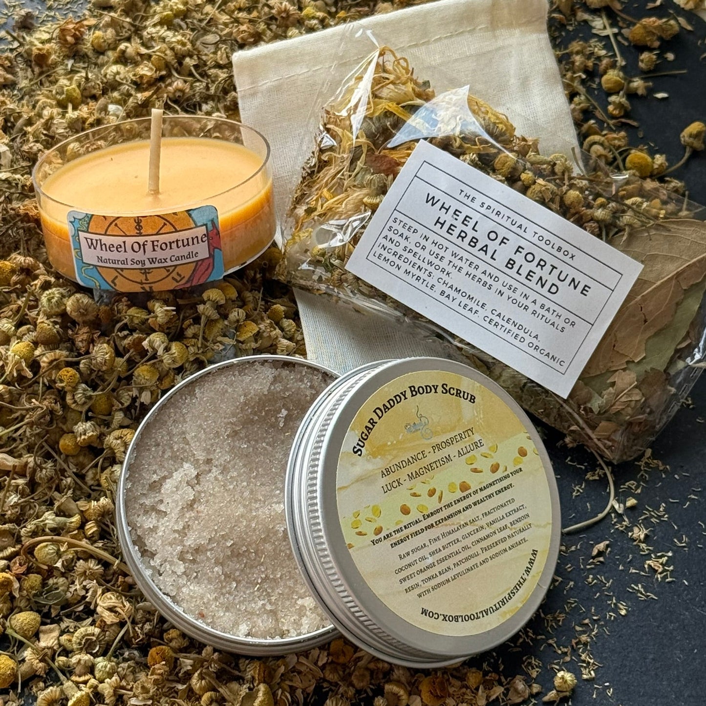 Herbal blend with a candle, body scrub, and packaging on a dark surface.