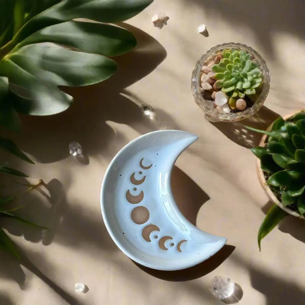 Ceramic crescent moon dish with engraved designs on a wooden surface with yellow flowers in the background