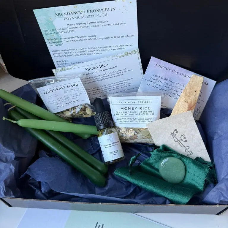 Abundance spell box with candles, oils, and other items on a dark background