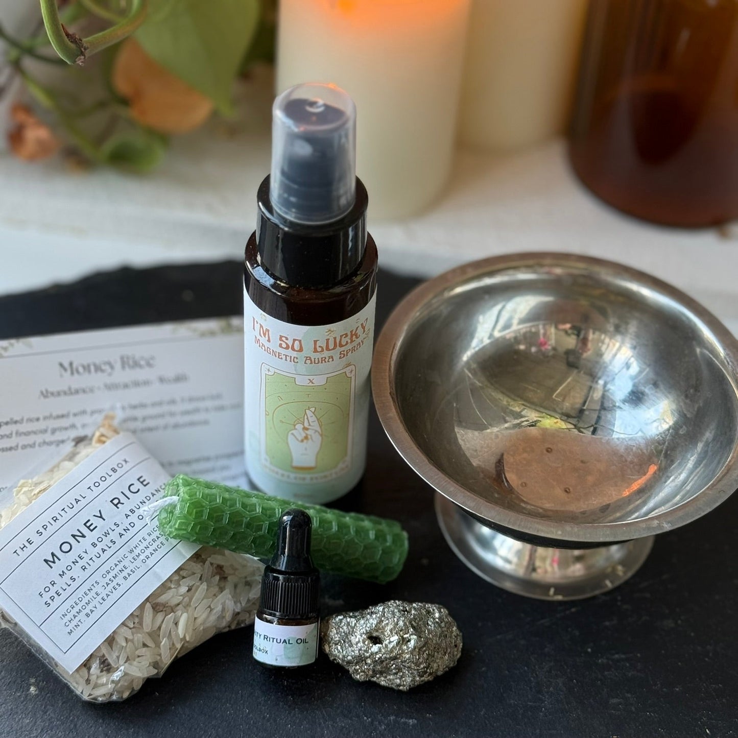 Herbal incense sticks, a bottle of 'So Lucky' spray, and other items on a dark surface with candles in the background.