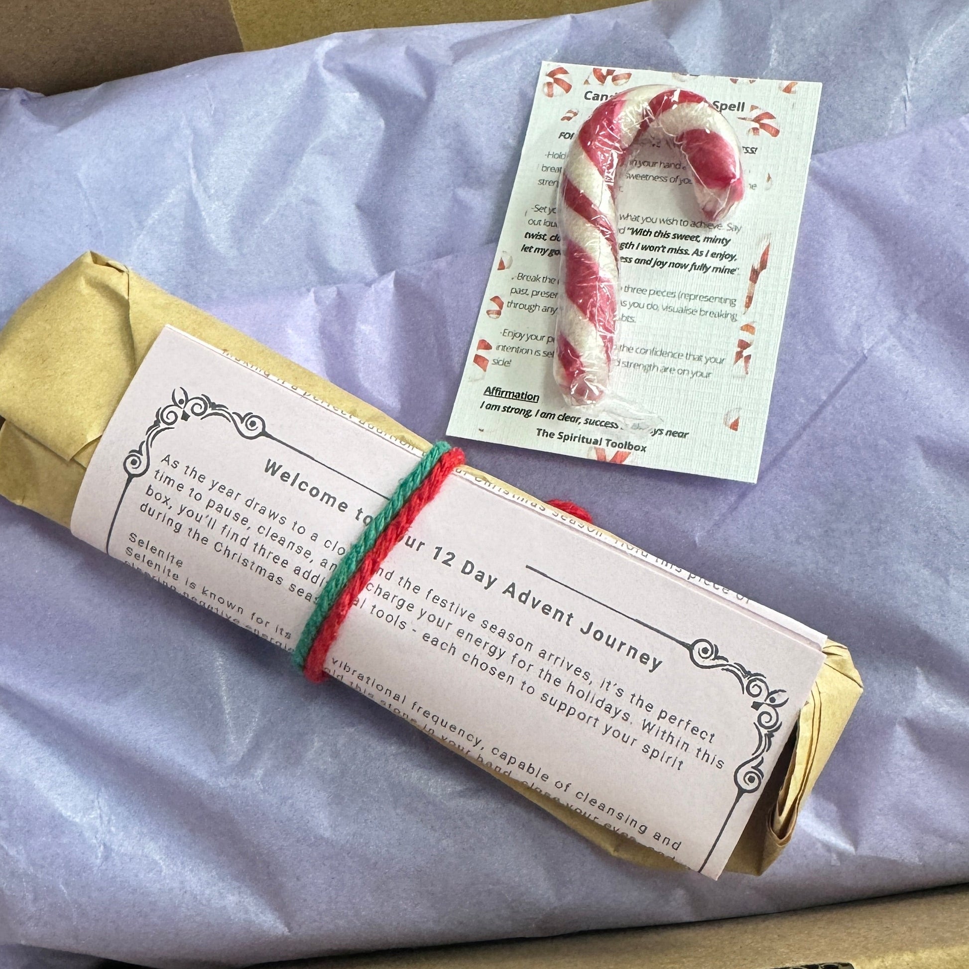 Christmas-themed items including a candy cane and a card on a purple surface.