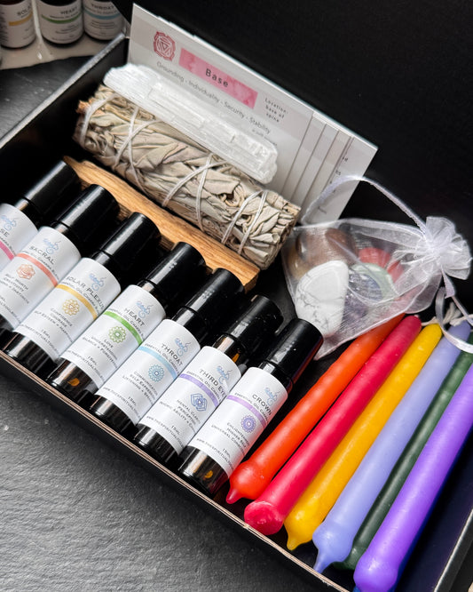 Set of essential oil bottles, candles, and other items in a box on a dark surface.