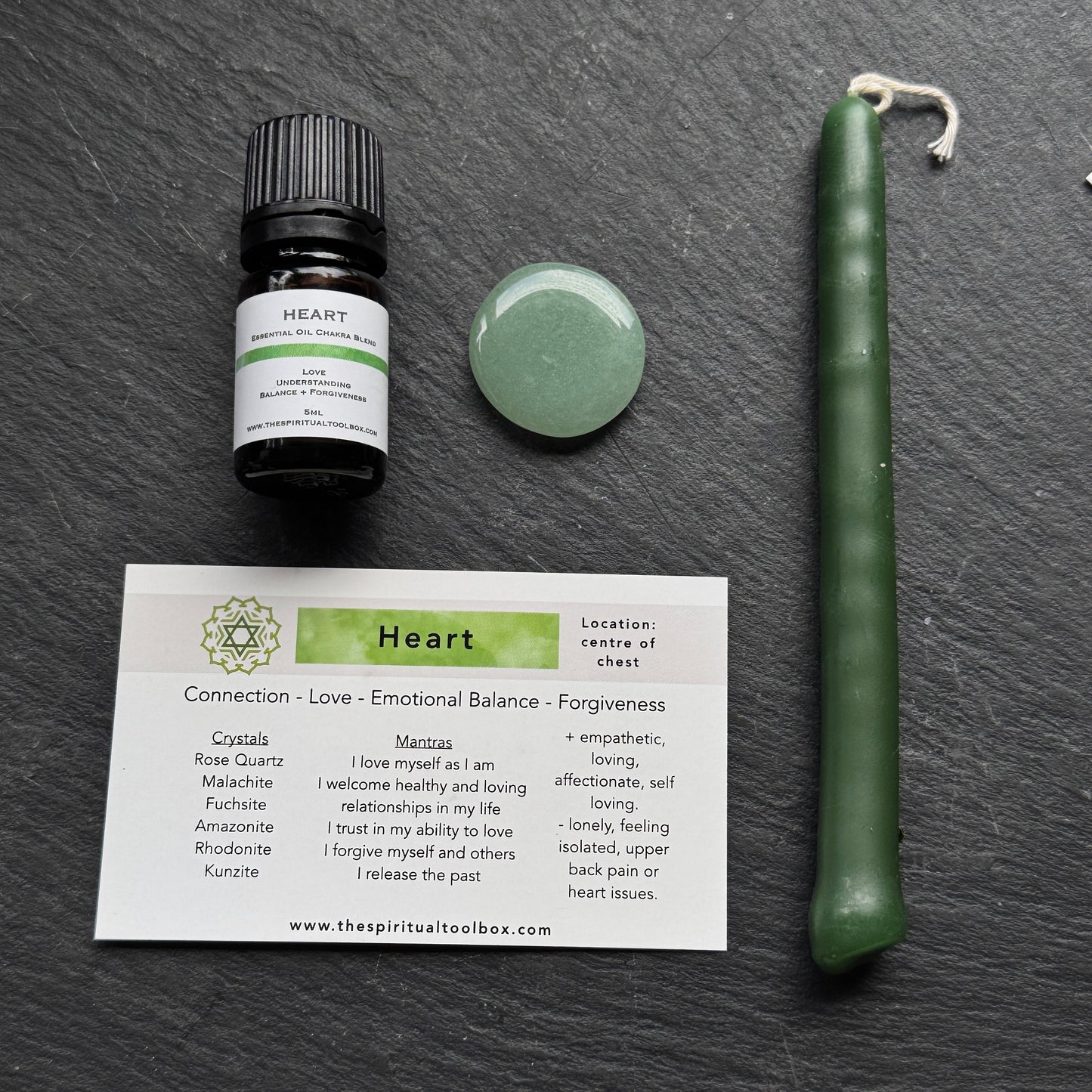 Heart-themed product set including a bottle, candle, and card on a dark surface