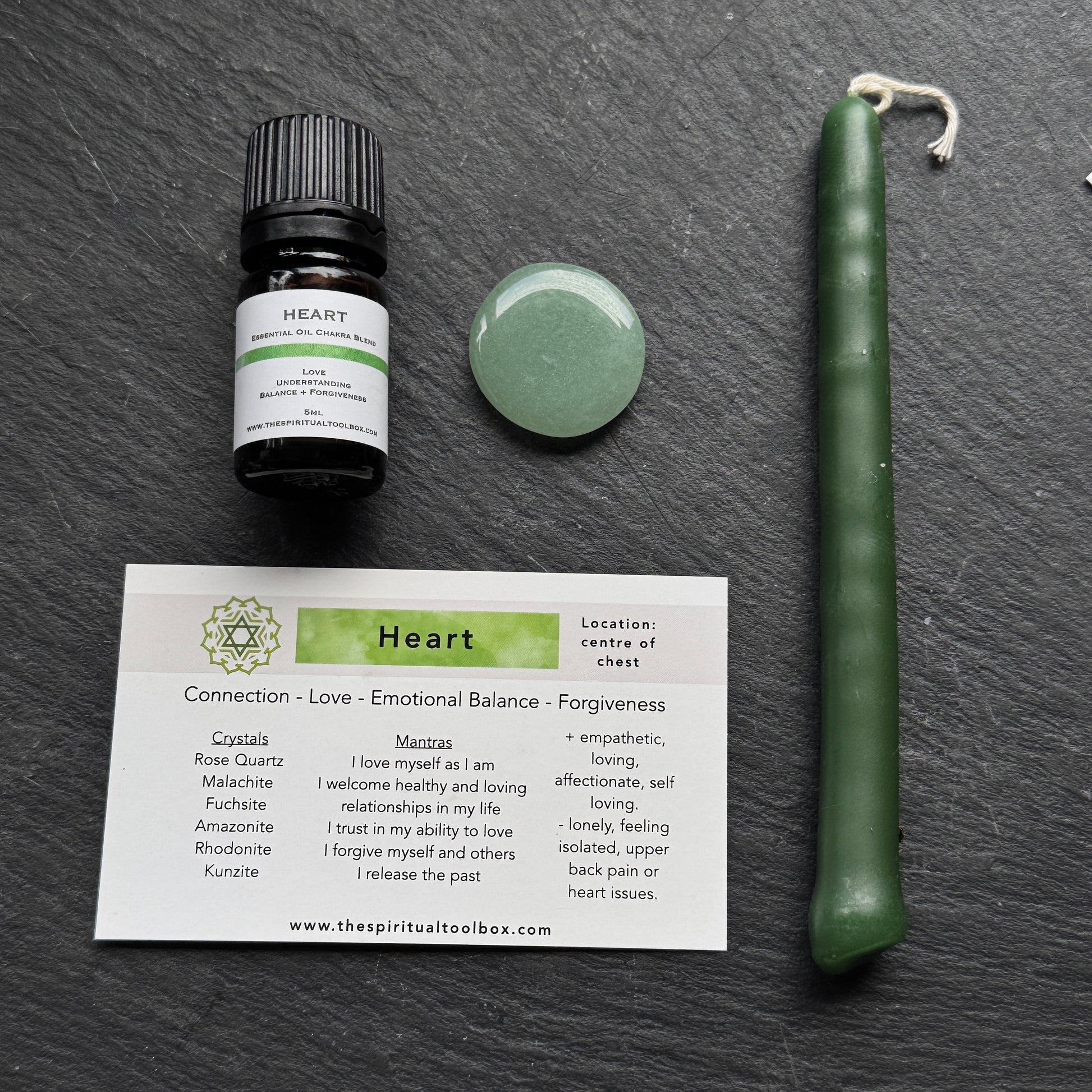 Heart-themed product set including a bottle, candle, and card on a dark surface