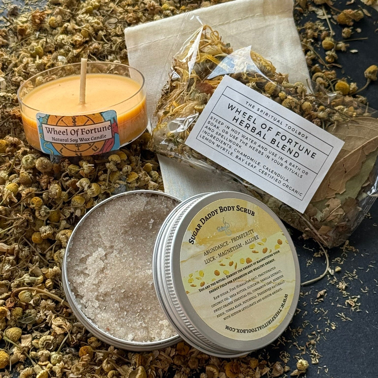 Herbal blend with a candle, body scrub, and packaging on a dark surface.