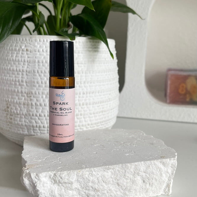 Small bottle with a orange label on a white surface with a plant in the background