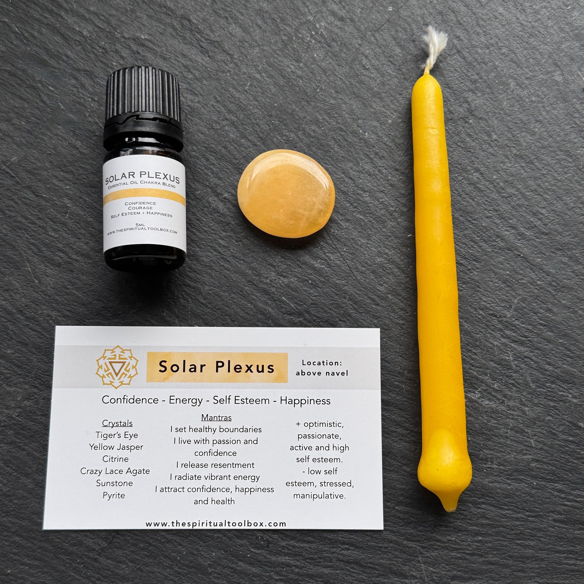 Solar Plexus essential oil bottle, candle, and card on a dark surface