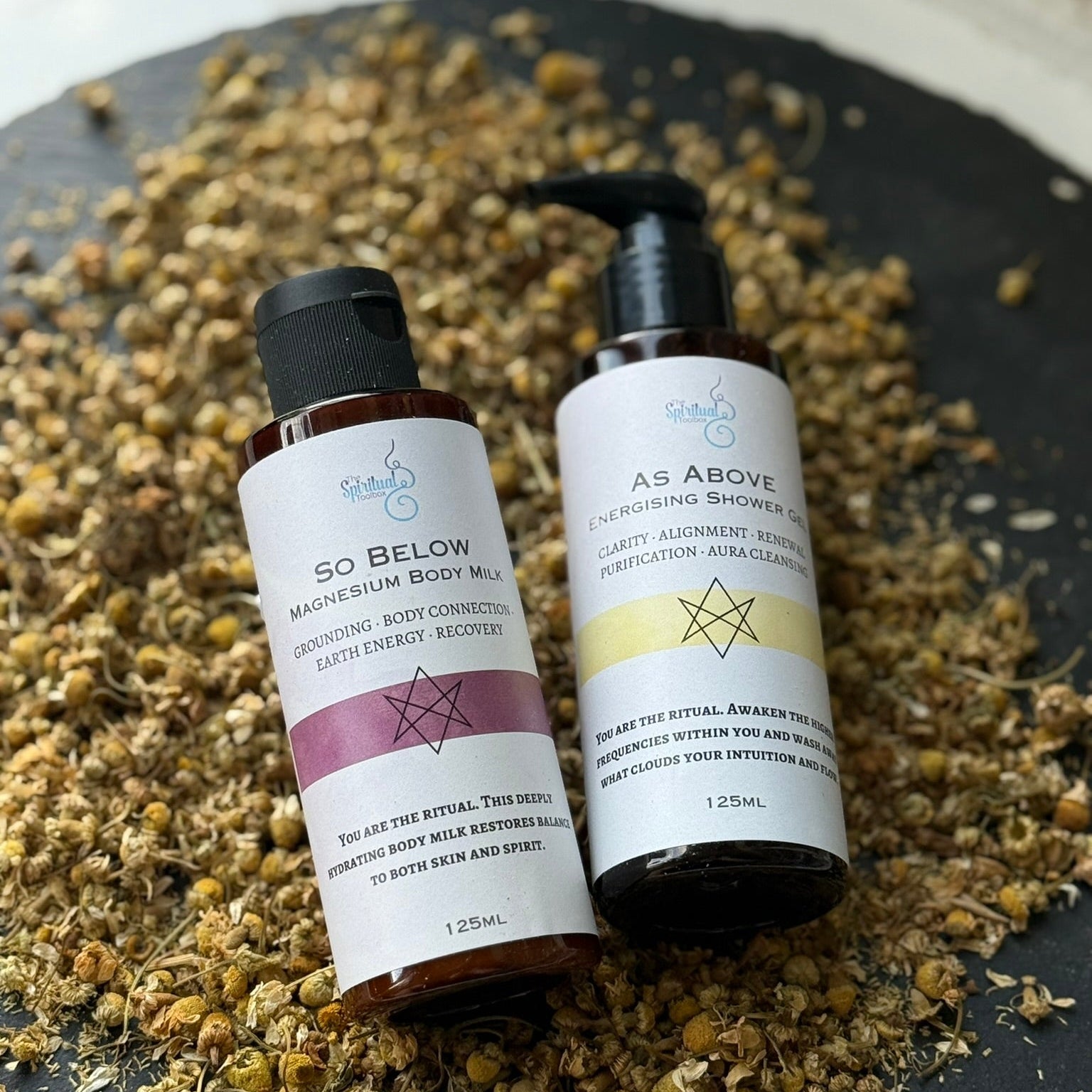 Two skincare products on a dark surface with dried herbs