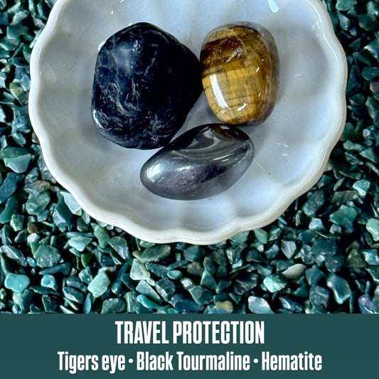 Three stones (Tigers eye, Black Tourmaline, Hematite) in a white shell on a textured green surface with text 'Travel Protection'.