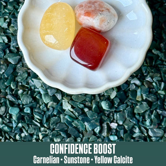 Shell with colored stones on a textured green surface, labeled 'Confidence Boost'.