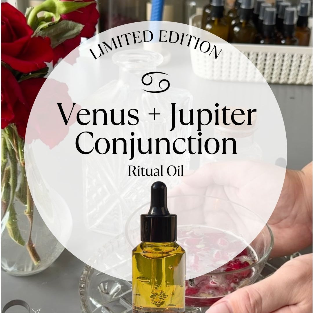 Venus and Jupiter Conjunction ritual oil bottle with dropper held by a hand, surrounded by flowers and jars.